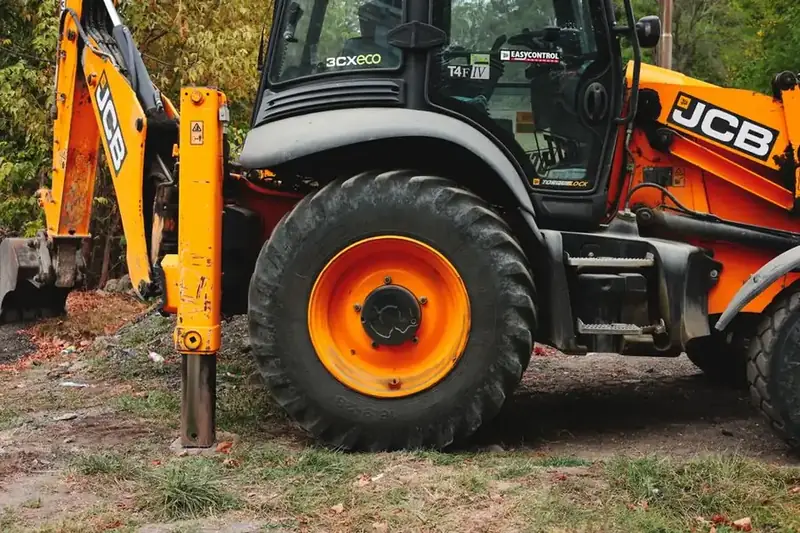 Excavator digging out a driveway sub-base on a sloping plot