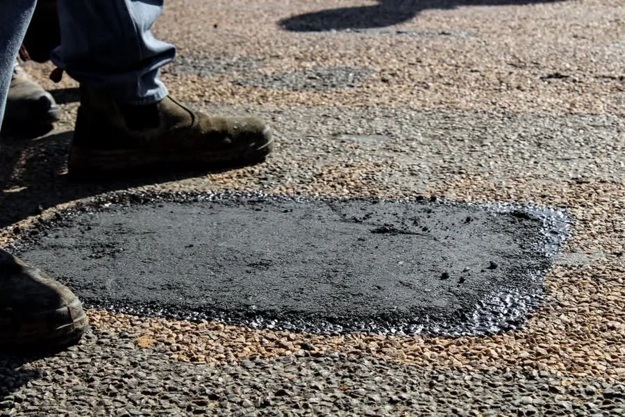 A patch of new black surfacing laid into an existing driveway after excavation