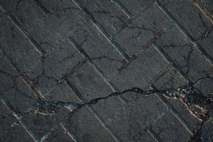 A cracked existing hard surface being assessed as a base for resin overlay