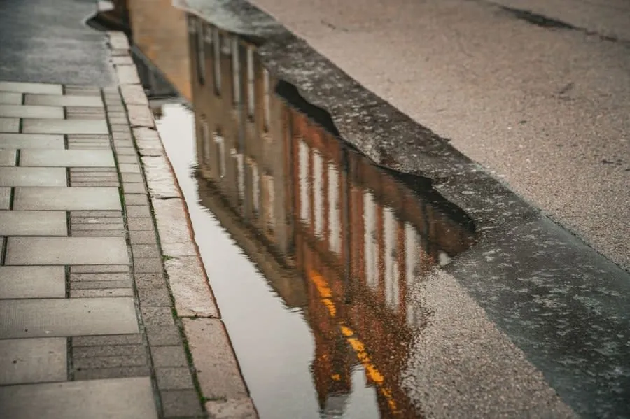 Rainwater standing on a street surface outside houses after heavy rain