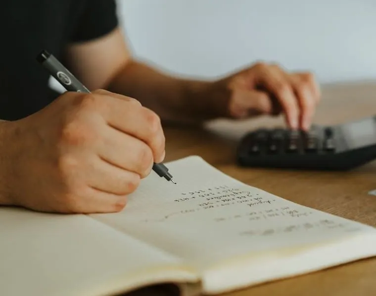 A buyer working through survey notes and repair budgets with a calculator