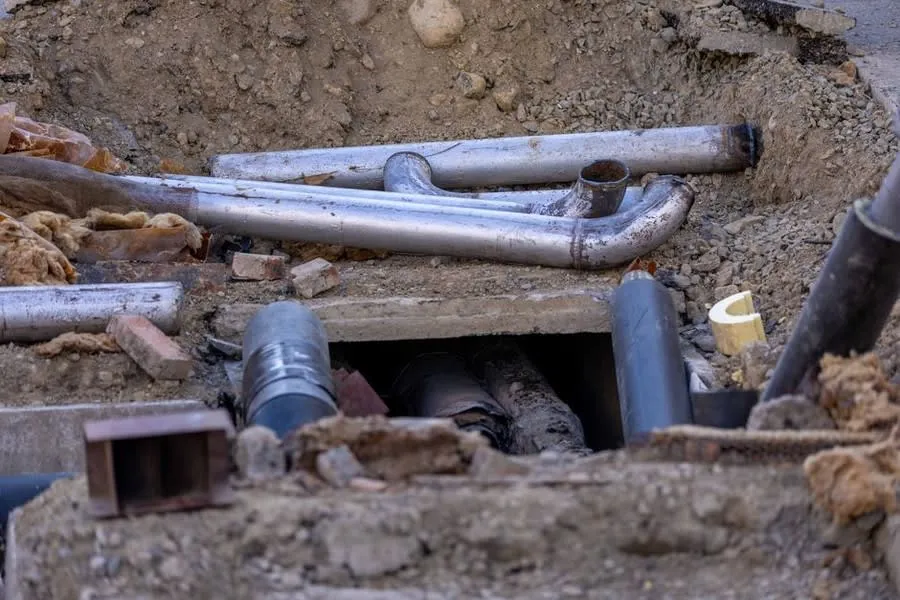 Utility pipes exposed in an open trench during excavation work