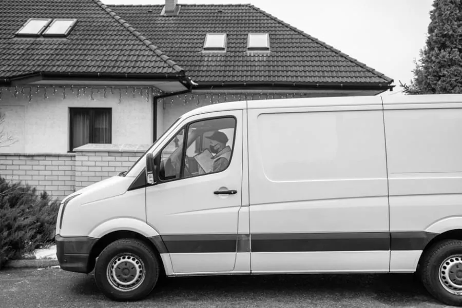 A white van parked on a driveway outside a house